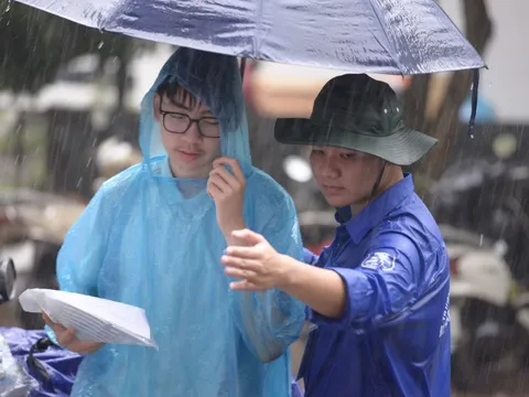 Tình nguyện viên đội mưa che cho thí sinh dự thi vào trường THPT chuyên ĐH Sư phạm Hà Nội