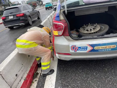 Cảnh sát giao thông đội mưa thay lốp xe cho người dân trên cầu Chương Dương