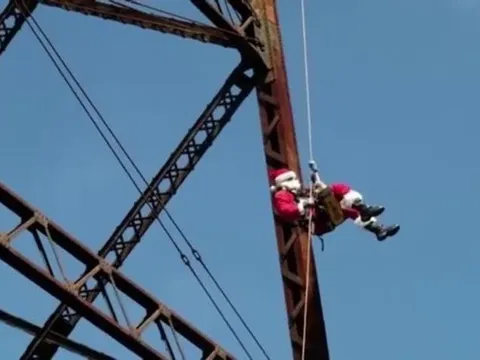 Ông già Noel đu dây từ trên cầu, mang niềm vui đến cho trẻ em nghèo